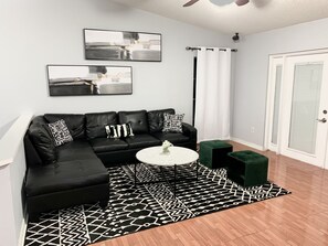 Shown is the newly decorated living room with sectional sofa & seating ottomans