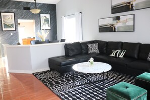 Shown is the newly decorated living room with sectional sofa & seating ottomans