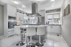 Kitchen with gas stove, fan hood, fridge, microwave, oven, dishwasher, utensils 
