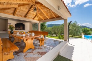 Comfortable and covered outdoor dining area with a traditional barbecue