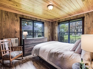 The queen bed in the main house master bedroom is surrounded by nature views and accessed through bedroom two.
