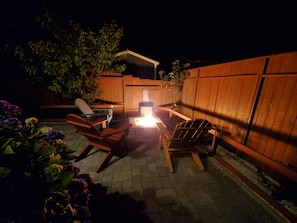 Propane-fueled stone fire pit warms coastal evening through copper fire glass