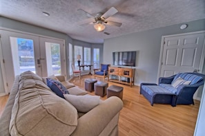 Bask in the comfort of this airy living room, complete with cozy seating, a smart TV, and sunlit views through expansive windows.
