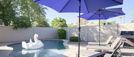 Private backyard oasis featuring heated pool, sun loungers, yard games, BBQ grill, and fire pit.