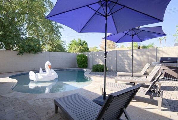 Private backyard oasis featuring heated pool, sun loungers, yard games, BBQ grill, and fire pit.