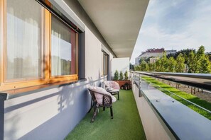 A balcony with wooden furniture, overlooking a lush garden and green outdoor space, providing a relaxing setting.