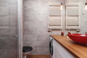 A bathroom with light tiles, a washing machine, and a towel rack, designed for practicality and comfort.