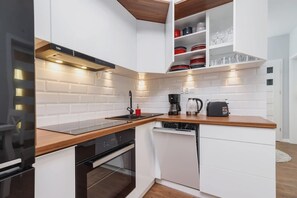 A sleek kitchenette featuring wooden countertops, white cabinets, and modern appliances like a stovetop and kettle.