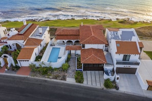 Birds eye showing the property, pool, and proximity to the fairway lined ocean