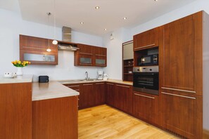 An open-plan living room and kitchen with wooden furniture, a dining table, and a comfortable seating area.