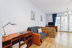 Another bedroom area shot showcasing a wooden bed with blue accents, a desk, and ample natural light from large windows.