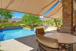 Patio seating with awnings out, pool and BBQ area