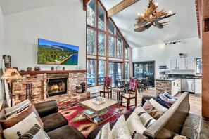Cozy Cabin Living Room · Open layout to the dining room, kitchen, and outside deck · Big window · Smart TV · Free WiFi · Wood-burning fireplace · & more!