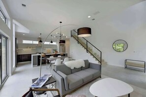 Open Living Dining Kitchen to floor to ceiling glass looking out at back yard