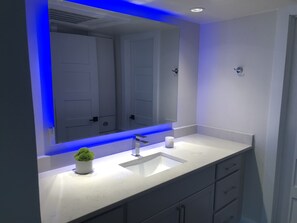 Luxury hotel style bathroom with backlit mirror, toiletries & towels