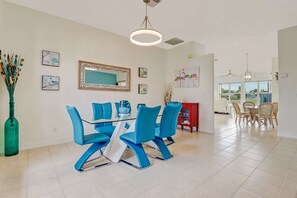 The formal dining area, open to the sitting room, features a unique and modern glass table that seats 6.