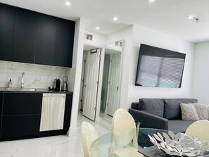 Stylish living and dining area with cozy sofa group and 70-inch Smart TV.