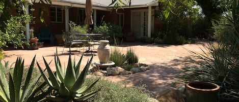 Sunny backyard patio with fountain, table and chairs with umbrella.