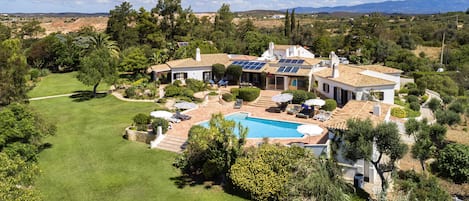 The villa with the pool area, garden, tennis court and putting green