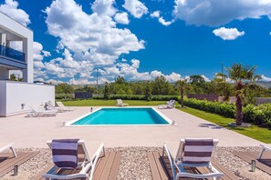 Private, heated pool with spacious sun deck in front of the villa with 10 sun chairs