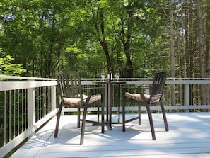 Large, furnished deck, surrounded by trees.