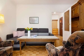 A vintage-style living room with a double sofa bed and two retro-style armchairs.