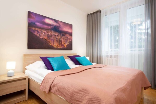 A double bed in one of the bedrooms with pink bedding and a stylish artwork above the bed.