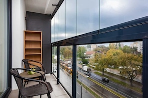 A stylish balcony with glass railings, wooden flooring, and a pair of chairs for enjoying the view outside.