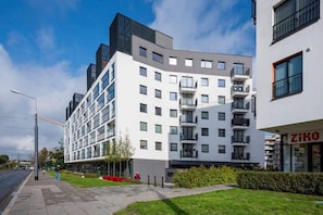 A shot of a modern apartment building surrounded by landscaped greenery and clear pathways.