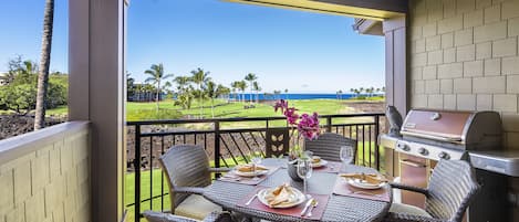 Private lanai of this Kona Hawai'i vacation rental with golf course and ocean views, grill, and seating for 4.