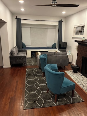 Living room area with TV, couches, cozy chairs in front of the fireplace. 