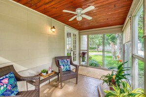 The "Florida Room" style porch with tropical foliage is one of the features of Bleu Daze Cottage.