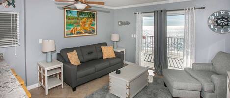 Living room with balcony access, a ceiling fan and a sofa sleeper