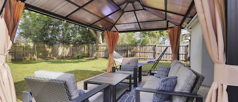 Comfortable conversation set under covered pergola with sunshade and bug screen