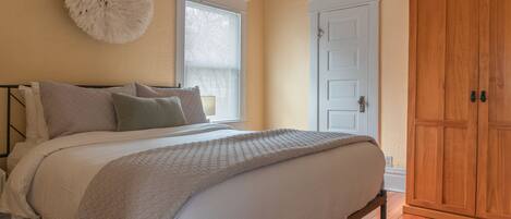 Bd 1: Queen bed w/ 100% cotton linens, dresser, wardrobe, door to bathroom