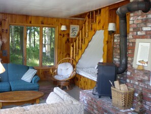 Living room with two couches, a desk, a bed, and a wood-burning stove