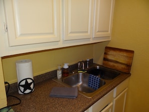 Kitchen has a stainless steel, double sink, dishes, pots, pans & utensils.