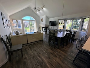 The dining/living area is a sunny open concept space with dining table that seats 6 and comfortable furniture that surrounds the gas fireplace. Access to the back deck with golf course views!