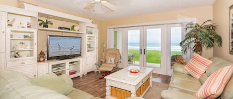 Living room with a smart TV, sofas, ceiling fan, and sliders to the oceanfront patio