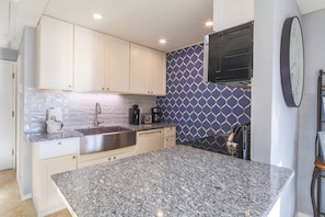 The renovated kitchen features granite countertops, white cabinetry and a tiled backsplash.