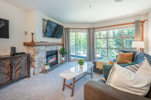 Living Room - Enjoy the beautiful forest scenery, cozy up in front of the fireplace, enjoy Netflix or cable on the large wall-mounted TV.