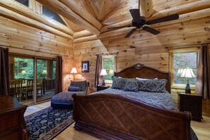 Master bedroom has vaulted ceiling framed by natural log beams over the king size bed.