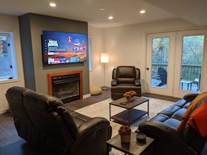 Lower level family room with top grain leather reclining seating and 65" Roku TV