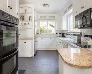 Well-equipped eat-in chef’s kitchen with double oven and granite countertops
