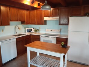 Full kitchen with pots, pans, dishes, utensils.