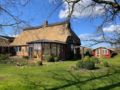Idyllic thatched roof house from 1860 with winter garden and foresight