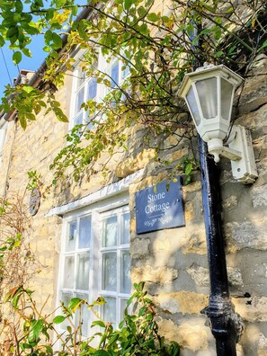 Plentiful plants and roses over the Stone Cottage entrance.