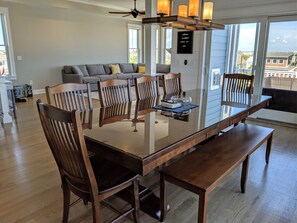 Large wooden table, with a glass top, 8 chairs and a bench, and ocean views.