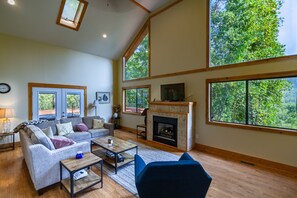 Bright living room with large picture windows, gas log fireplace and satellite TV