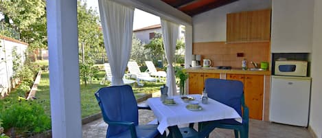 Il terrazzo coperto dotato di cucina esterna, tavolo con sedie, vista giardino.